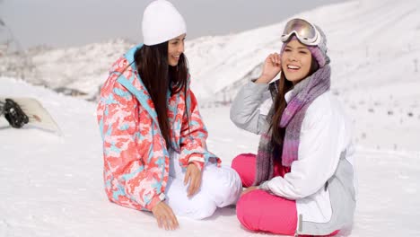 Two-young-female-friends-chatting-in-the-snow