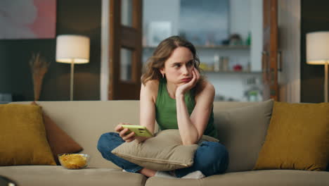 una mujer nerviosa usando el teléfono sentada en el sofá. una chica emocional lanzando el sofá del teléfono celular.