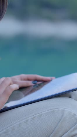 person using tablet outdoors by water