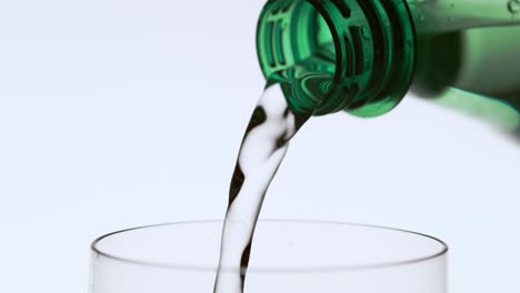 water pouring from green bottle into drinking glass