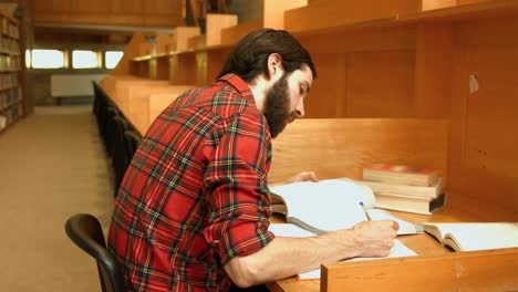 Estudiante-Leyendo-Un-Libro-De-La-Biblioteca