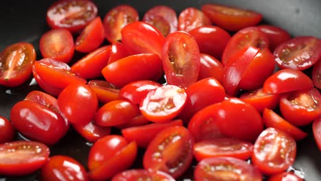 close up shot in slow motion of heated large pan with olive oil and putting halved cherry tomatoes in