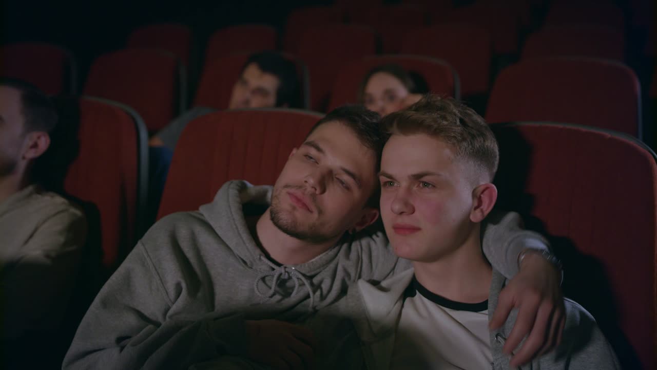 pareja de gays abrazándose en el cine. hombres homosexuales abrazándose en el cine