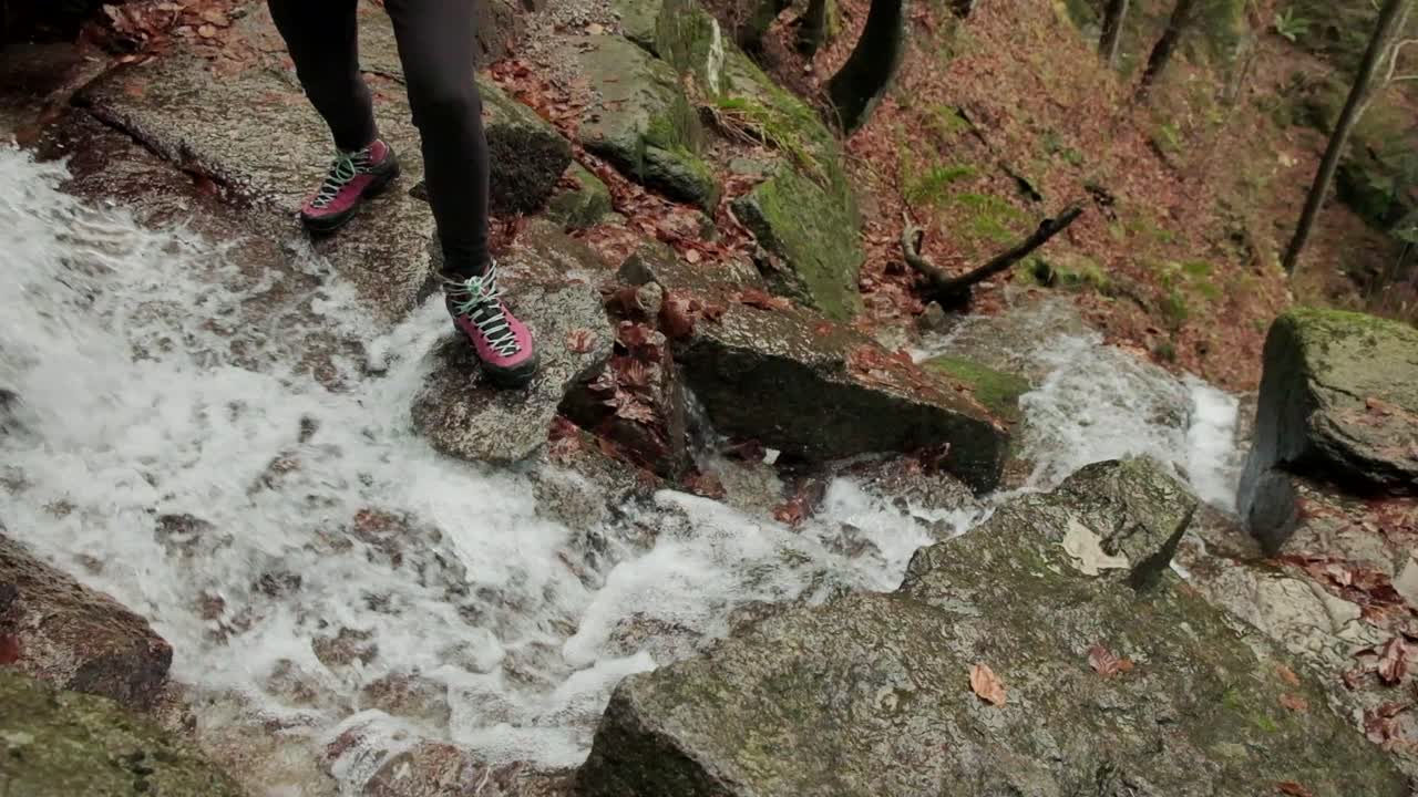 Lady walking through a waterfall in Slow motion as the water falls underneth her. Hiking waterproof boots. Waterfall of Veliki Sumik in the eastern part of Slovenia