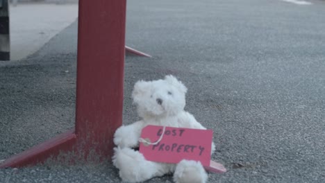 teddy with lost property tag left on train platform medium tilting shot