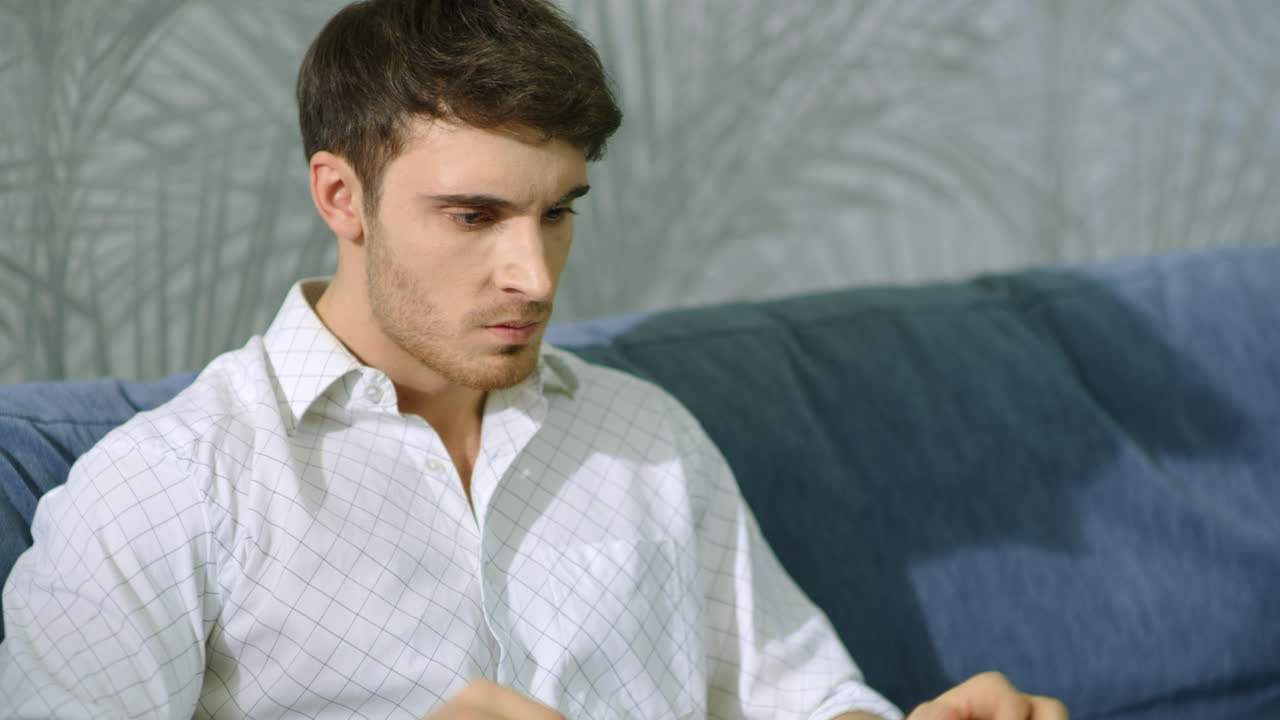 악의적인 남자가 실내에서 노트북을 때리고 화난 남자가 실내에서 컴퓨터를 사용합니다.