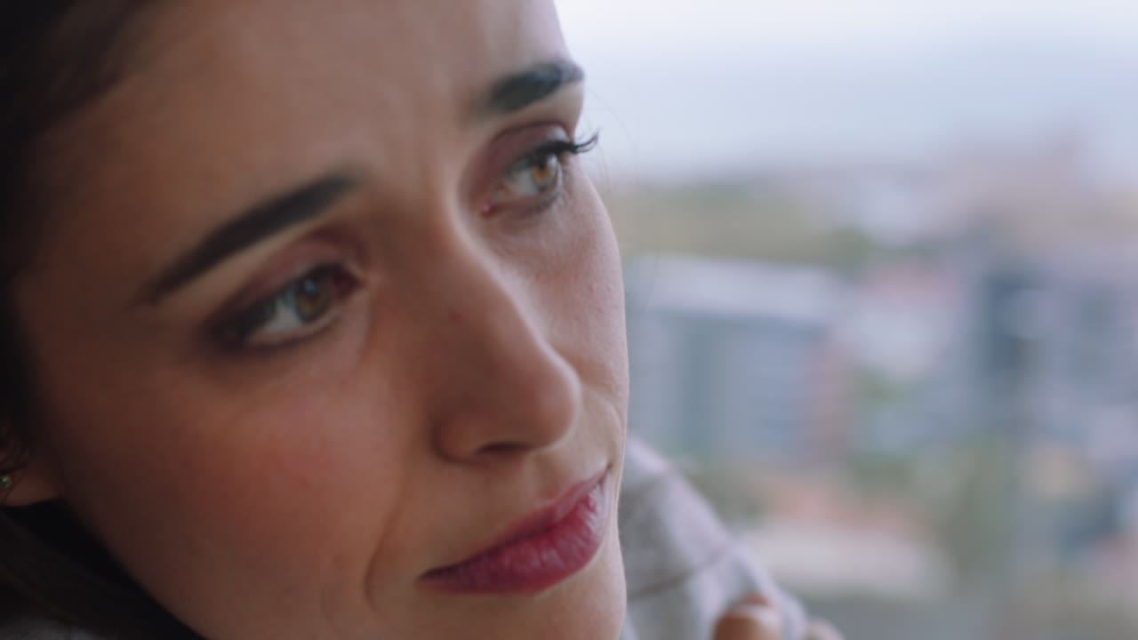 mujer joven feliz mirando por la ventana sintiéndose acogedora disfrutando de la vista de la ciudad en el frío día de invierno