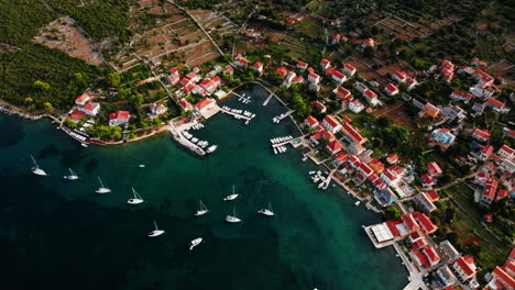 sailboats anchored off shore of ilovik island croatia, bird's eye view ascending drone shot