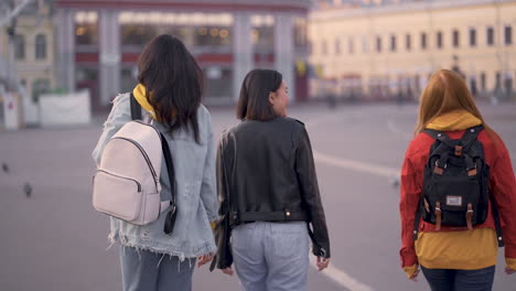 mujeres multiétnicas caminan juntas de la mano al aire libre