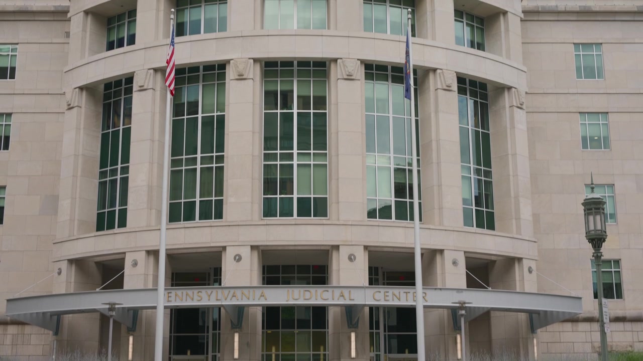 Inquadratura cinematografica grandangolare con movimento tilt-up che rivela il Pennsylvania Judicial Center nel centro di Harrisburg, Pennsylvania, mostrando l'architettura governativa moderna e la magistratura statale.