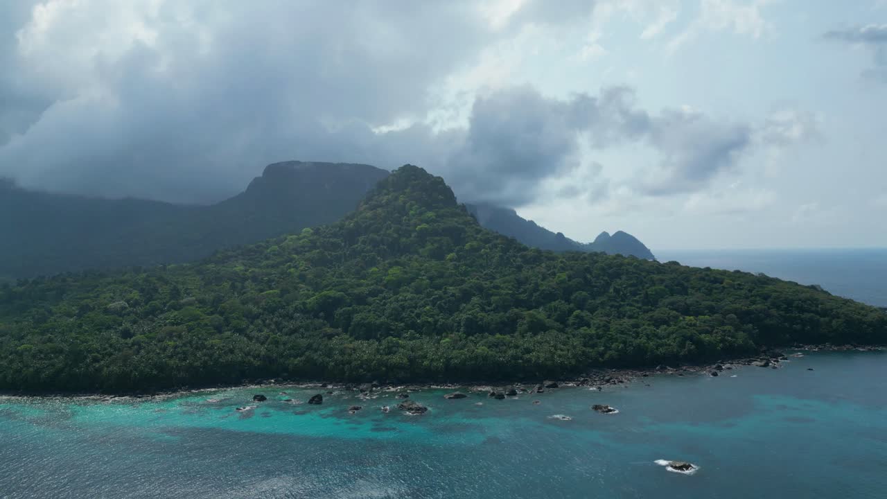 Aerial circular view descending over the coast of Príncipe Island with the island's beautiful mountains in the background.São Tomé e Principe,Africa