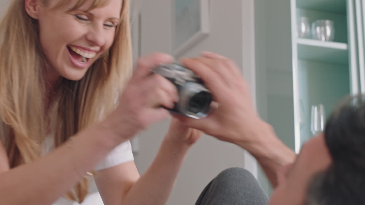 행복한 커플이 카메라를 사용하여 함께 사진을 찍고 소파에서 집에서 재미있게 로맨틱한 관계를 즐기고 있습니다.