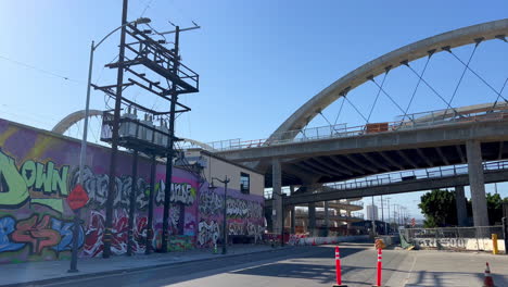 establishing shot of downtown industrial area, sixth street bridge and street art wall on clear sunny day in los angeles