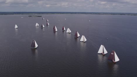 skutsje classic sailboats on dutch calm lake ready for a race, aerial