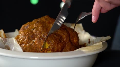 man chef slicing a whole roasted and spiced cauliflower