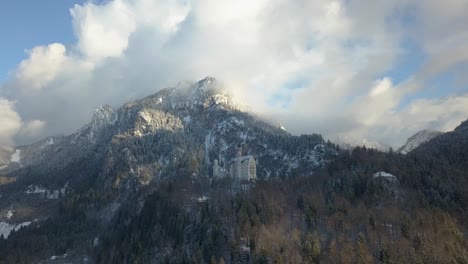 Neuschwanstein-Castle-against-mountains-and-clouded-sky,-Füssen,-Bavaria,-Germany