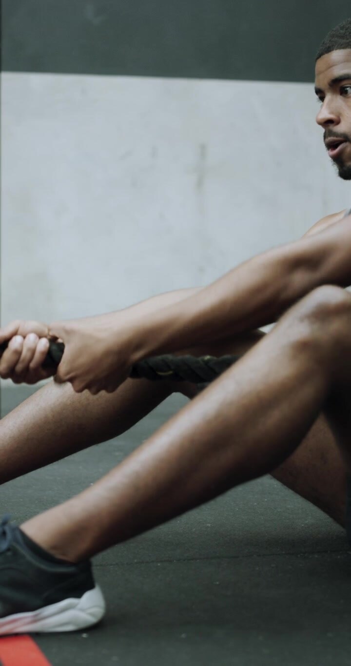 Athletic Man Performing Seated Battle Rope Pulls in Gym
