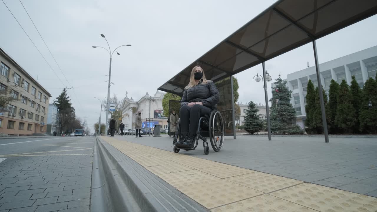 Woman in a wheelchair waiting for a bus at a bus stop