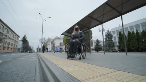 woman in a wheelchair waiting for a bus at a bus stop