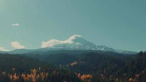 4k aerial snowy mountain in fall with colorful forest in foreground