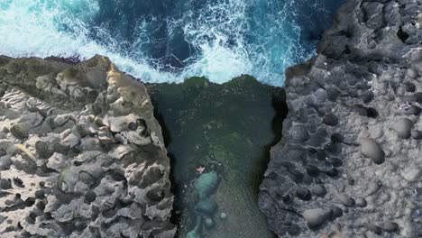 azure blue water waves break against eroded rocky shore in bali