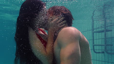 Junges-Paar-Küsst-Sich-Unter-Wasser-Im-Schwimmbad-Und-Genießt-Einen-Innigen-Kuss.-Romantische-Liebende-Tauchen-Im-Wasser-Auf-Und-Schweben-Mit-Blasen-In-Leidenschaftlicher-Intimität