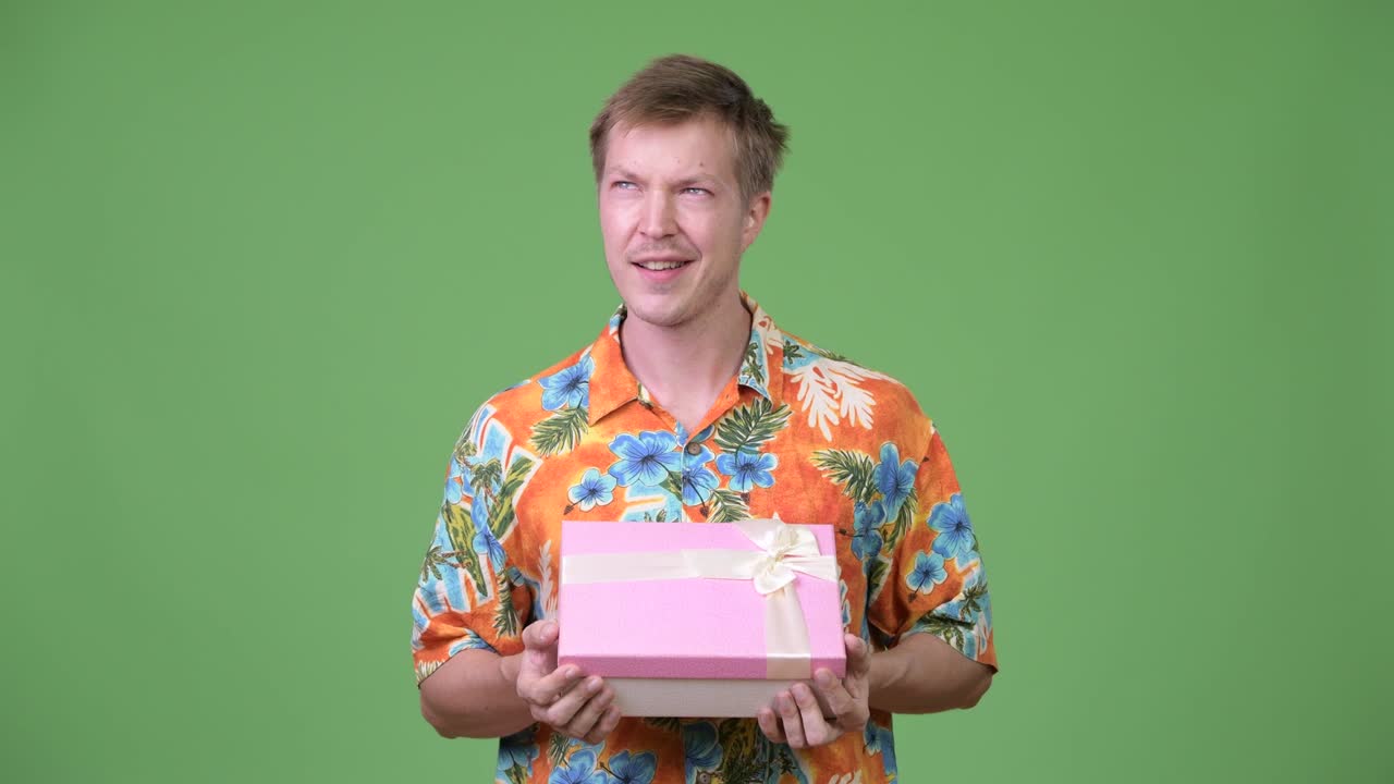 Young handsome tourist man holding gift box and thinking
