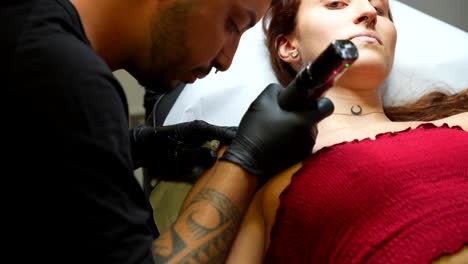 tattoo artist carefully tattooing young female customer and having conversation