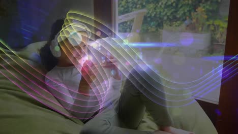 Abstract-design-moving-against-girl-using-digital-tablet-wearing-headphones