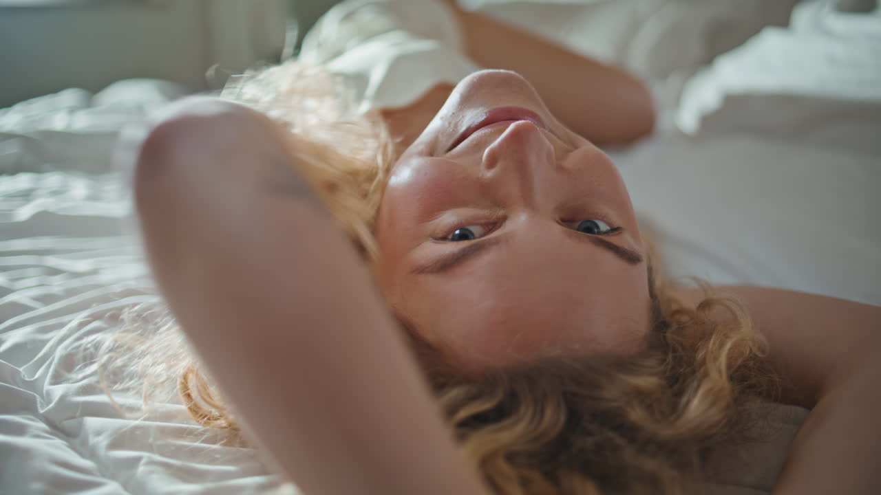Cheerful woman lying bed embodying relaxation and comfort at home closeup
