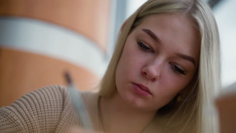 close-up of unhappy lady writing with focus, expressing concentration and seriousness, surrounded by a blurred background, conveying emotions through writing and reflection in a quiet setting