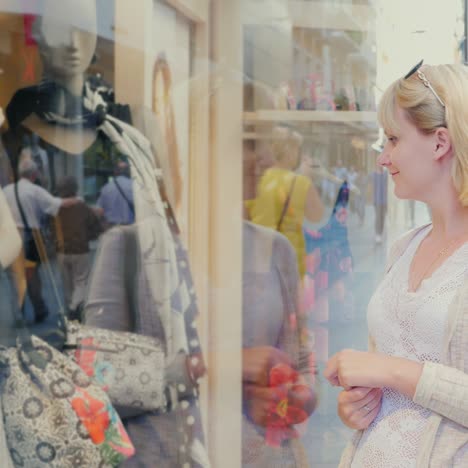 a young woman traveler looks at the window of a clothing store