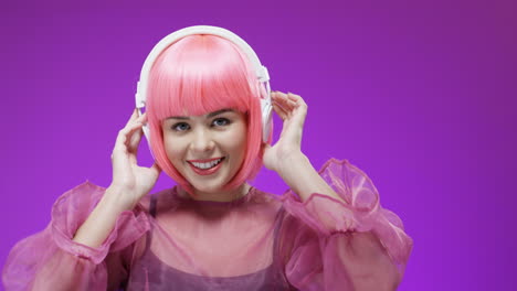 Portrait-Of-Beautiful-Woman-Wearing-A-Pink-Wig-And-Headphones,-Dancing-And-Laughing-To-The-Camera