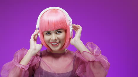 portrait of beautiful woman wearing a pink wig and headphones, dancing and laughing to the camera