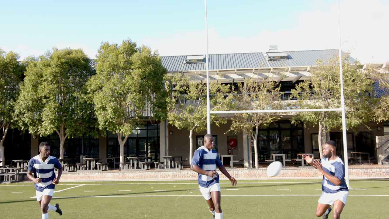 Playing rugby on field, african american men in sports uniforms running and practicing teamwork
