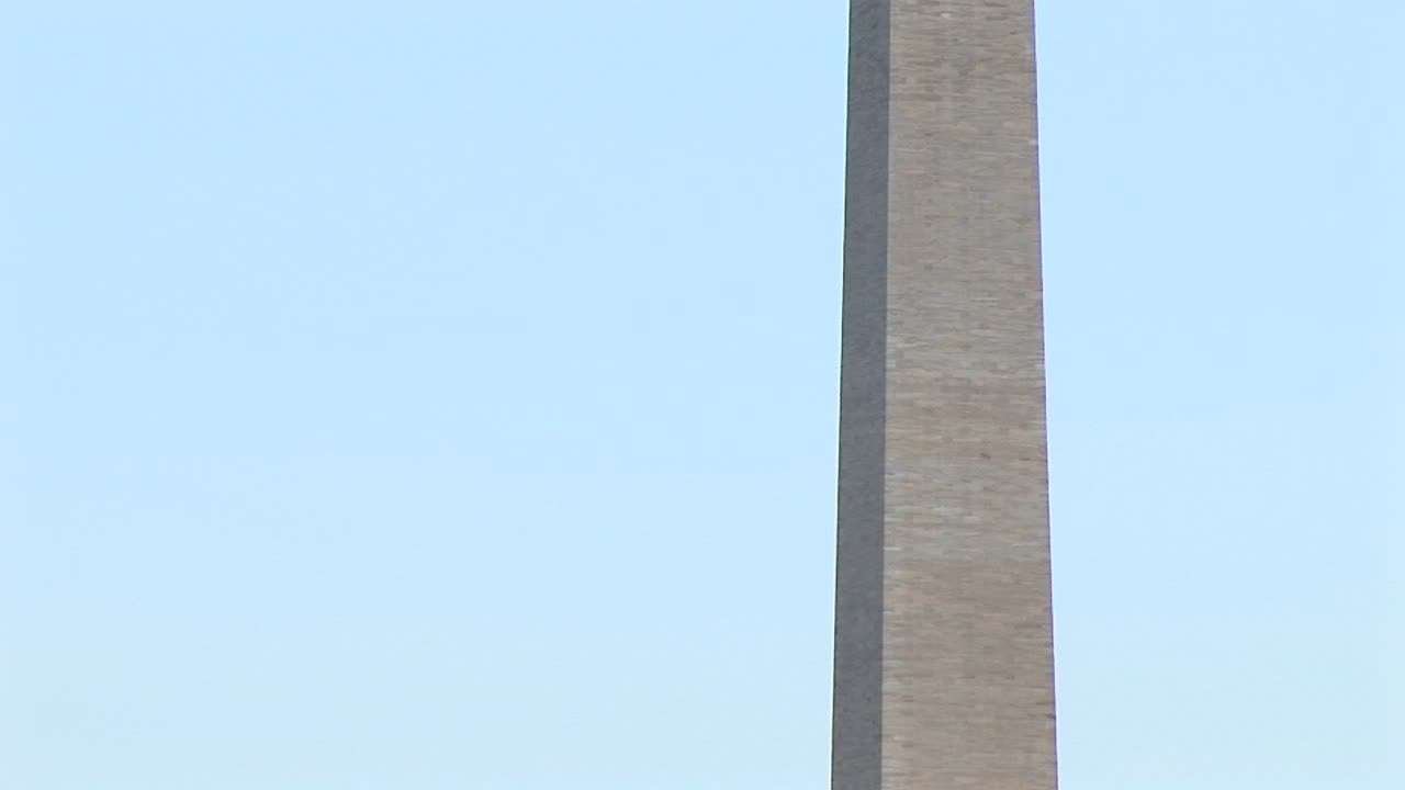 워싱턴 기념탑은 꽃이 만발한 벚나무 옆에 있고 꼭대기에 있는 카메라 팬업으로 둘러싸여 있습니다.