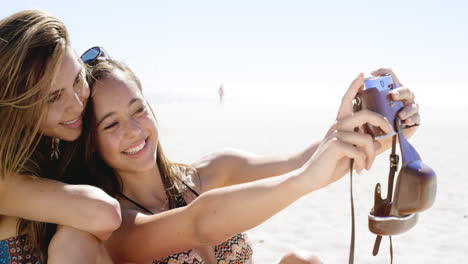 Close-up-of-three-teenage-girl-friends-taking-selfie-photograph-with-vintage-camera