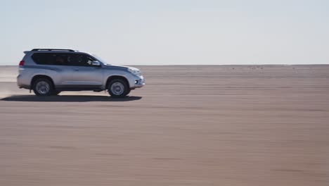 4x4 vehicles racing on sandy surface of sahara desert, handheld side view