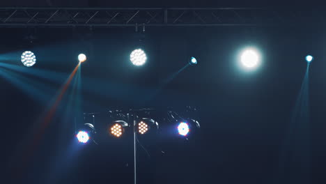 dark stage with colorful spotlights or several bright projectors. different projectors with lighting effects on scene in the evening.