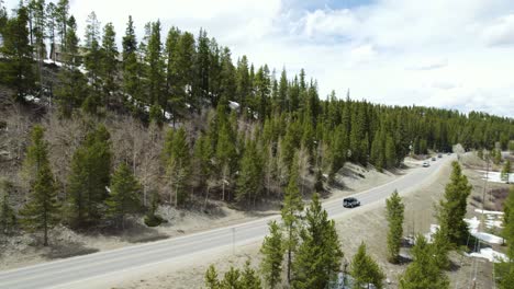 Jeep-wrangler-driving-through-snowy-mountains,-solo-adventure-road-trip-on-the-open-road