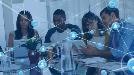 animation of network of digital icons against team of diverse colleagues using electronic devices