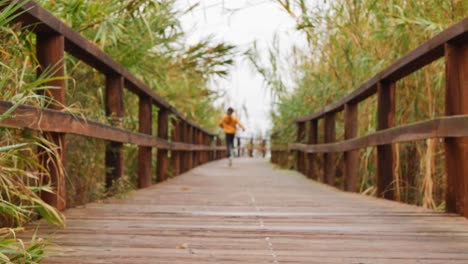 Happy-little-girl-running-and-jumping-on-a-wooden-walkway