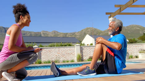 side view of mixed-race personal trainer exercising with determined senior black man in backyard 4k