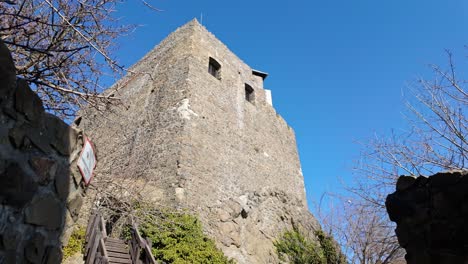 looking up at the medieval tower of hollókő castle, hungary. this stone structure stands tall against a clear blue sky, showcasing its historical significance and defensive architecture.