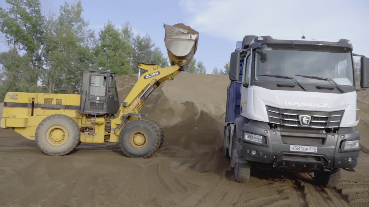 Excavator Loading a Truck with Sand