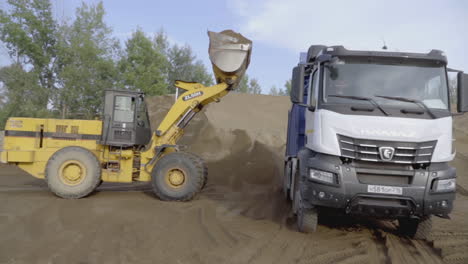 excavator loading a truck with sand