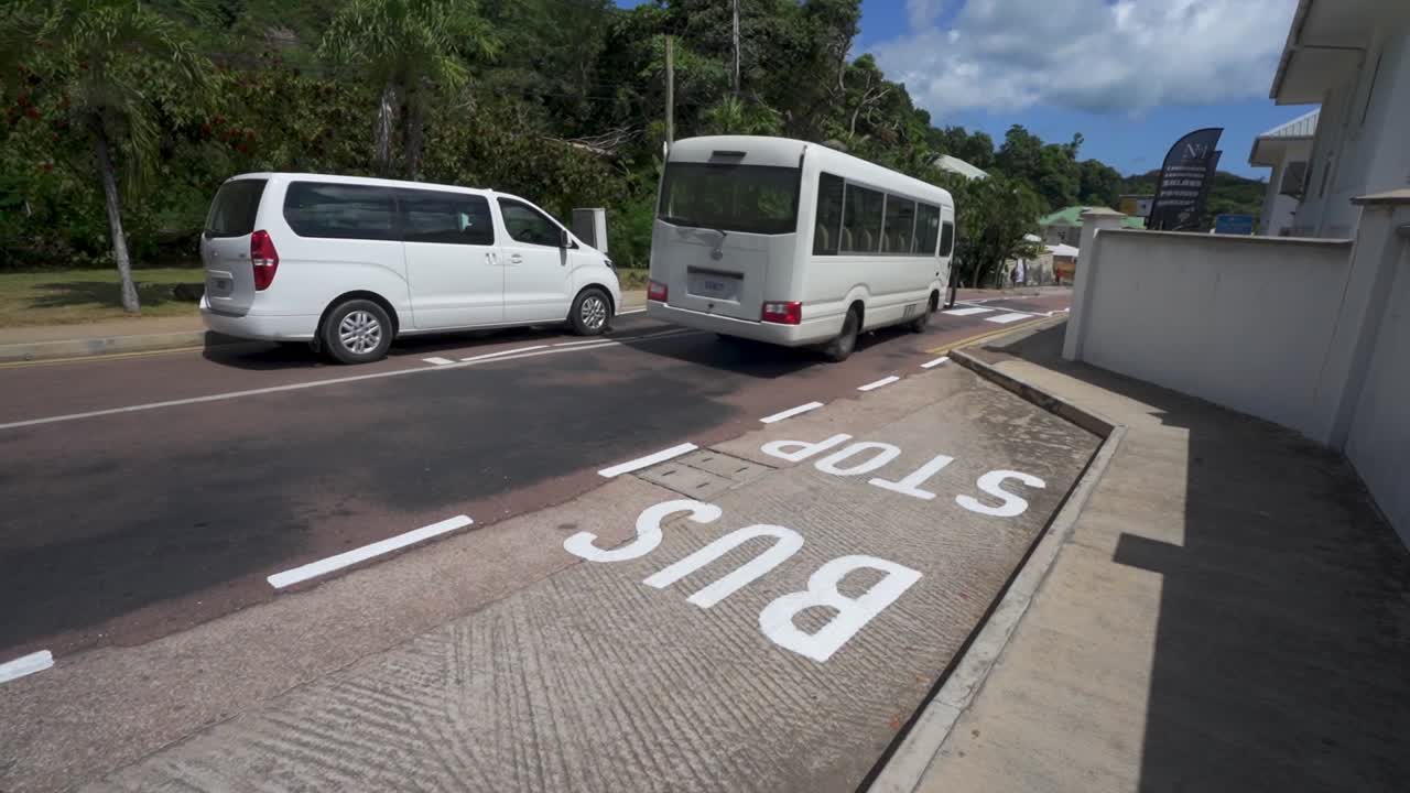 autobús público pasando lentamente por la parada de autobús en seychelles