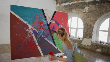Female-artist-emotionally-creates-masterpiece-of-abstract-painting-in-studio,-slowmo