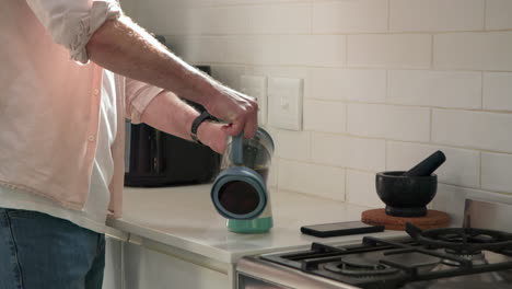 senior man preparing coffee with french press in cozy kitchen at christmas, at home