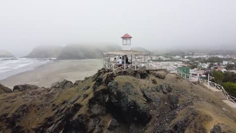 Orbit-Shot-Of-People-In-Pergula-Watching-Panoramic-Sea-View-In-Foggy-Weather,-Peru